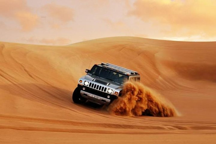 Experience the rush of dune bashing in a Hummer H2 navigating Dubai's stunning sand dunes while capturing unforgettable memories surrounded by the serene desert landscape.